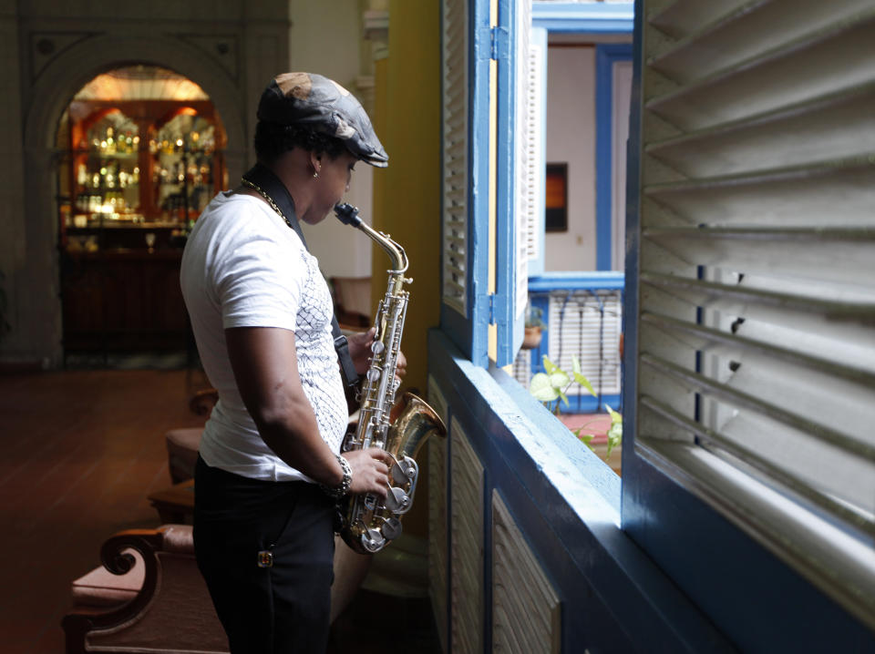 In this picture taken on April 17, 2012, a musician rehearses beside a louvered window at a restaurant in Old Havana, Cuba. (AP Photo/Kathy Willens)