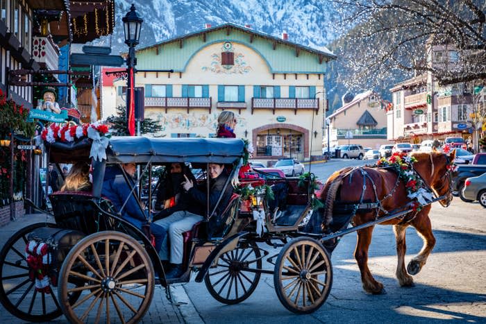 Winter town with Christmas wreathes and garland decorating the buildings and a horse drawn carriage with holiday flowers