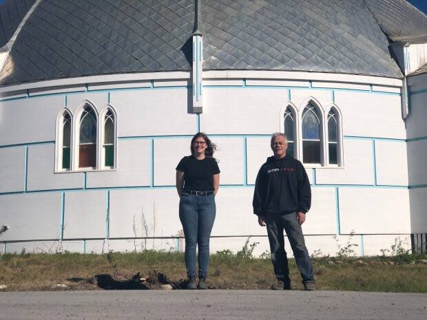 Permafrost scientist Alice Wilson and Project Uplift coordinator Peter Clarkson stand in front of Inuvik's Our Lady of Victory Catholic Church, better known as the igloo church. Its floor began dropping a couple of years ago as a result of the freeze-thaw cycle of permafrost the church is built on. (Mackenzie Scott/CBC - image credit)