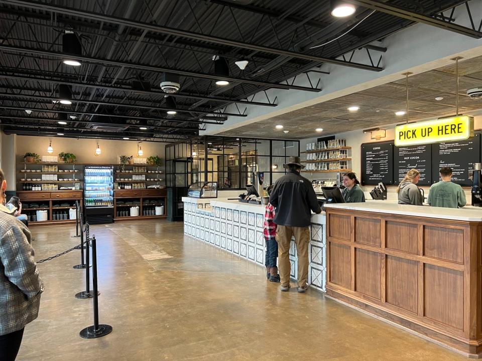 A coffee shop counter with people in front of it.