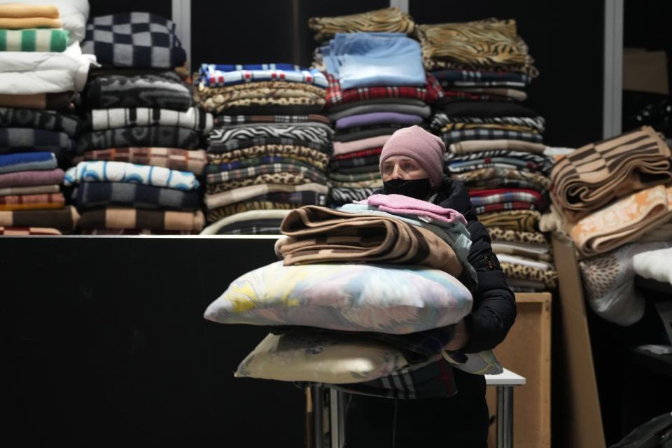 FILE - A Ukrainian refugee carries pillows and blankets at a refugee center in Nadarzyn, near Warsaw, Poland, Thursday, March 31, 2022. The U.N. refugee agency says more than 5 million refugees have fled Ukraine since Russian troops invaded the country. The agency announced the milestone in Europe’s biggest refugee crisis since World War II on Wednesday, April 20, 2022.(AP Photo/Czarek Sokolowski, File)