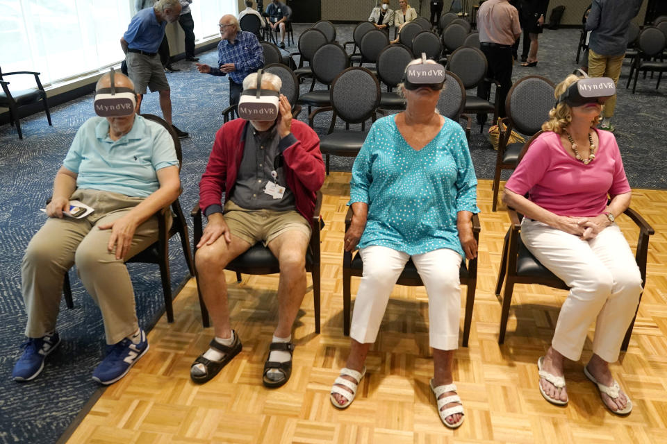 Residents of John Knox Village wear goggles as they participate in a virtual reality study, Tuesday, June 1, 2021, in Pompano Beach, Fla. The senior community is in partnership with Stanford University's Virtual Human Interaction Lab on a study to see how older adults respond to virtual reality and whether it can improve their sense of wellbeing. From left to right are Bruce Voelkel, John Dalsimer, Andrea Hipskind, and Janet Anding. (AP Photo/Lynne Sladky)