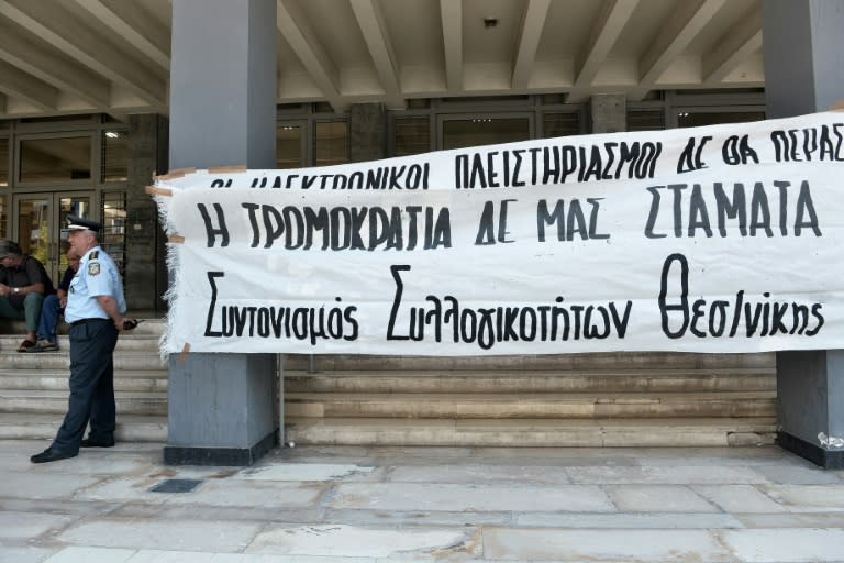 A policeman stands next to a banner reading "Auctions online won't pass. Terrorism does not stop us." outside of the courthouse as demonstrators protest against real estate auctions in Thessaloniki in June