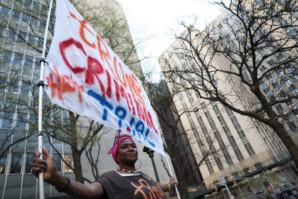 A protester holds a banner against Donald Trump outside the courthouse (Reuters)