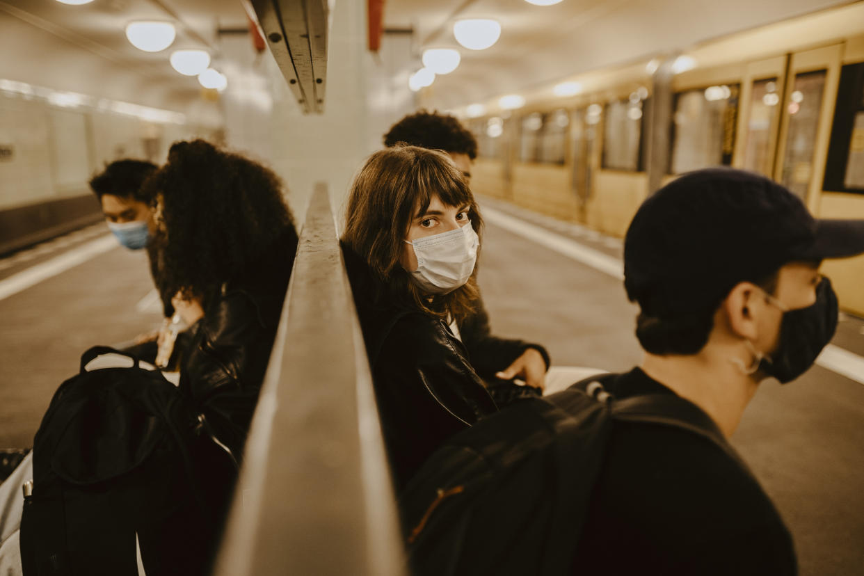 Travelers wear masks as they sit in a subway station.