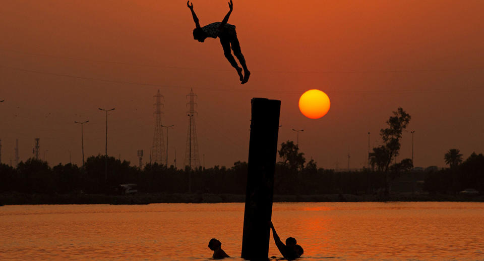 TOPSHOT - Iraqi youth swim in the Shatt Al-Arab river by the port of Maqil amid a heatwave in the southern Iraqi city of Basra on June 29, 2021. (Photo by Hussein FALEH / AFP) / The erroneous mention[s] appearing in the metadata of this photo by Hussein FALEH has been modified in AFP systems in the following manner: June 29, 2021] instead of [March 21, 2021]. Please immediately remove the erroneous mention[s] from all your online services and delete it (them) from your servers. If you have been authorized by AFP to distribute it (them) to third parties, please ensure that the same actions are carried out by them. Failure to promptly comply with these instructions will entail liability on your part for any continued or post notification usage. Therefore we thank you very much for all your attention and prompt action. We are sorry for the inconvenience this notification may cause and remain at your disposal for any further information you may require. (Photo by HUSSEIN FALEH/AFP via Getty Images)