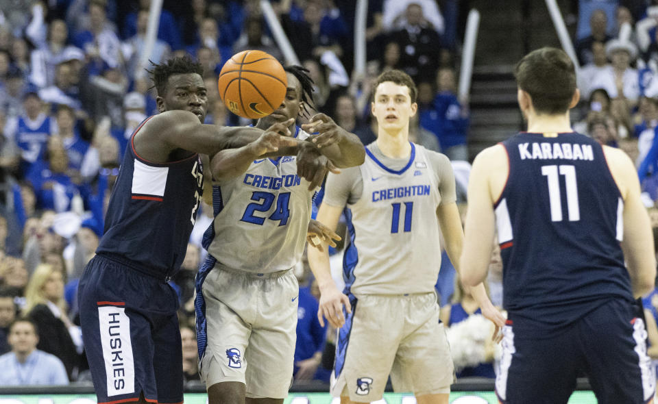 Creighton's Arthur Kaluma, second left, grabs an inbound pass intended for UConn's Adama Sanogo, left, with 2.3 seconds remaining in the second half of an NCAA college basketball game on Saturday, Feb. 11, 2023, in Omaha, Neb. Creighton defeated UConn 56-53. (AP Photo/Rebecca S. Gratz)