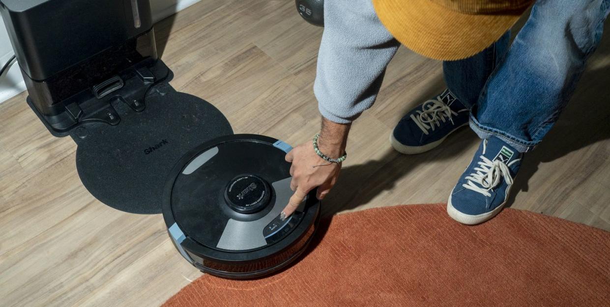 man pressing clean button on shark 2 in 1 robot vacuum and mop