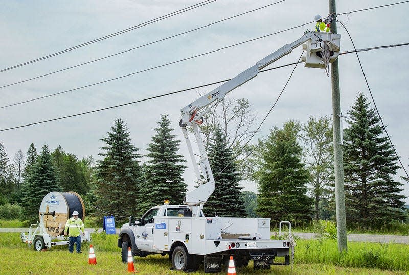 A crew attaches fiber cable to utility poles for Truestream, a fiber internet service being offered by Great Lakes Energy.