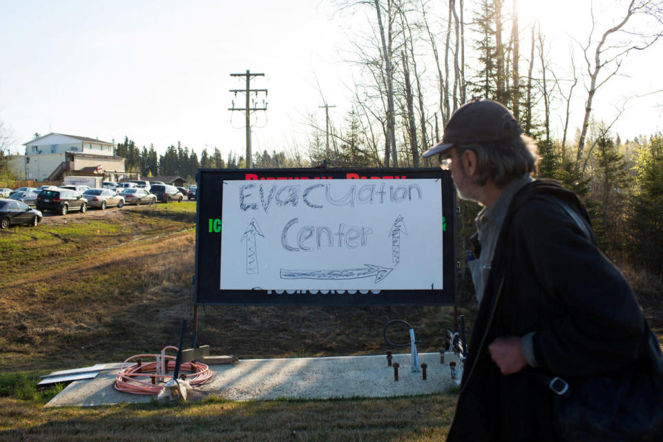 A resident of Fort McMurray walks past a evacuation centre sign put up in Anzac, Alberta, after residents were ordered to be evacuated due to a raging wildfire, May 4, 2016. REUTERS/Topher Seguin