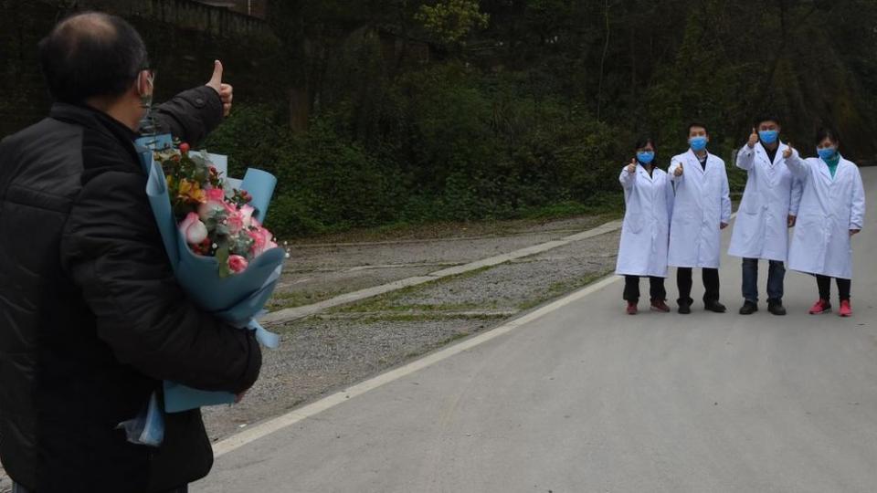 Un paciente curado de covid-19 saluda a los trabajadores médicos cuando es dado de alta del Centro de Salud Pública de Chongqing el 15 de marzo de 2020 en Chongqing, China.