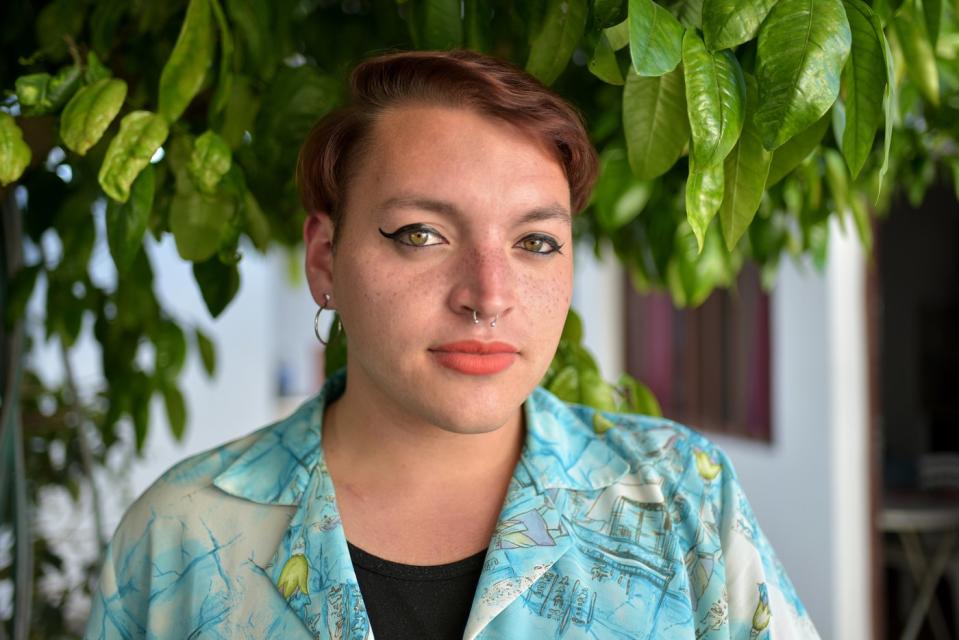 Someone is outdoors, facing the camera with a somewhat serious expression.