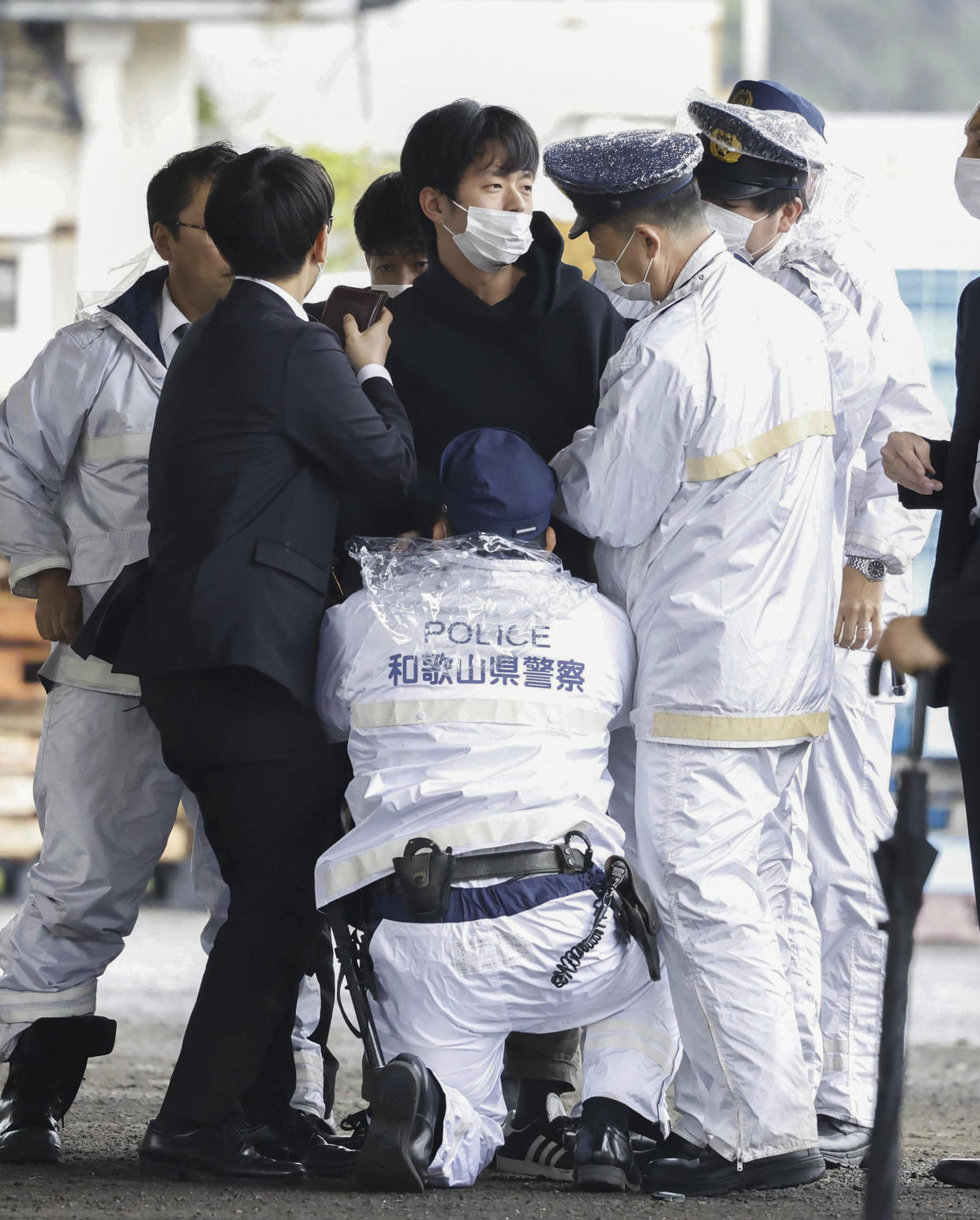 CORRECTS FIRST SENTENCE FOLLOWING THE SOURCE'S CAPTION CORRECTION - A man, center, is caught after what appeared to be a smoke bomb was thrown at a port in Wakayama, western Japan Saturday, April 15, 2023. Japan’s NHK television reported Saturday that a loud explosion occurred at the western Japanese port during Prime Minister Fumio Kishida’s visit, but there were no injuries. (Kyodo News via AP)