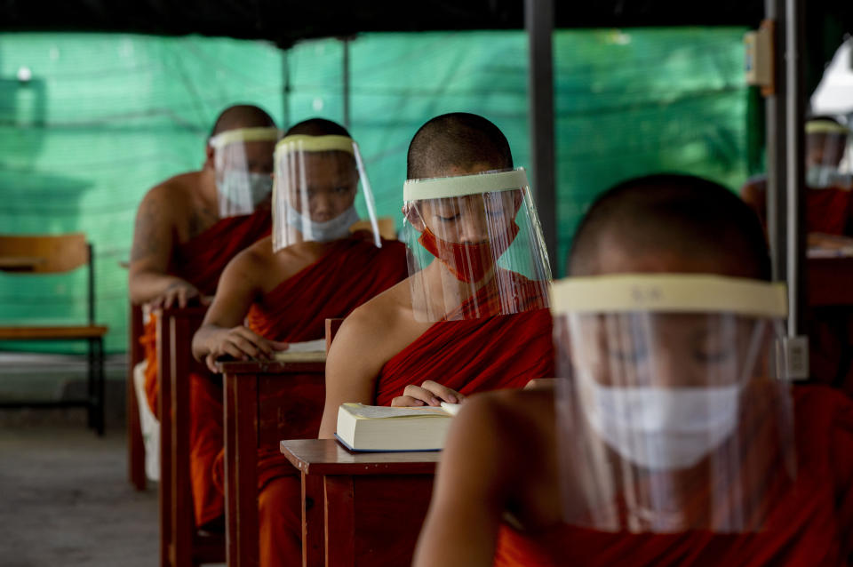 Novice Buddhist monks with protective masks and face shields, seated maintaining social distancing participate in a religious class at Molilokayaram Educational Institute in Bangkok, Thailand, Wednesday, April 15, 2020. All schools in Thailand were closed earlier than the scheduled school break due to the COVID-19 outbreak but about 200 novice monks remain in the monastic school due to travel restrictions and lockdowns implemented in provinces in Thailand. (AP Photo/Gemunu Amarasinghe)