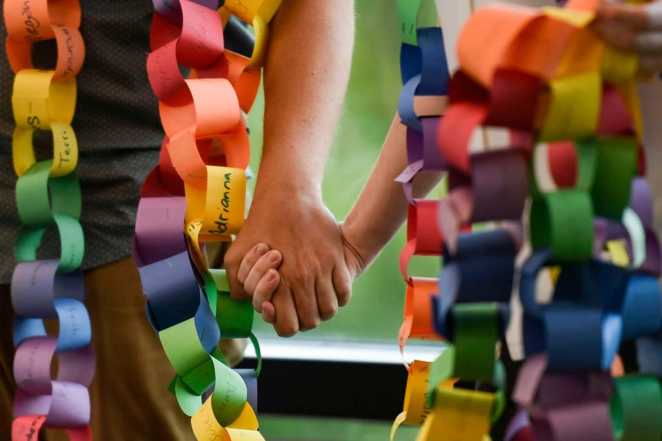 Community members hold hands as a paper chain hangs from their necks, serving as a petition, during a Greenville County Council public forum at Greenville County Square on Tuesday, Sept. 12, 2023. Community advocates delivered a petition calling to have the chairman removed from the library board.