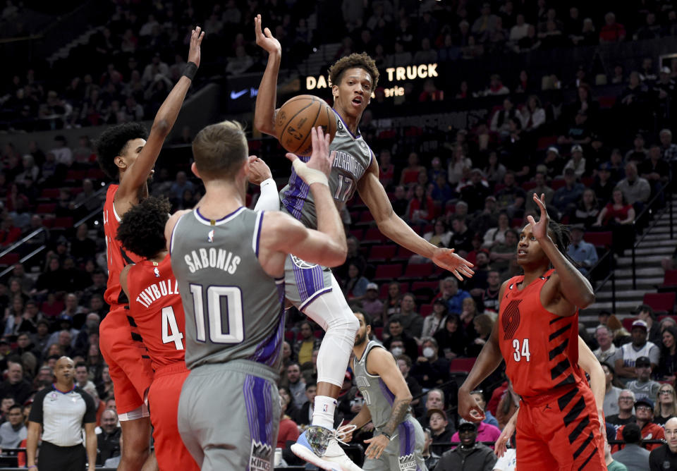 Sacramento Kings guard Kessler Edwards, center, passes the ball to forward Domantas Sabonis, left, as Portland Trail Blazers forward Jabari Walker, right, defends during the first half of an NBA basketball game in Portland, Ore., Wednesday, March 29, 2023. (AP Photo/Steve Dykes)