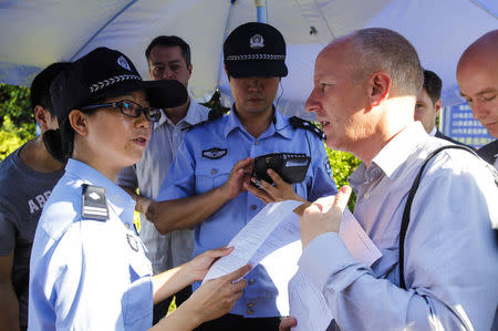 Beat Schmid (R), a Swiss diplomat, talks to police officers as he tries gain access to the courtroom where the trial of Chinese rights activist Guo Feixiong is ongoing, outside a court in Guangzhou, Guangdong province September 12, 2014. REUTERS/Alex Lee