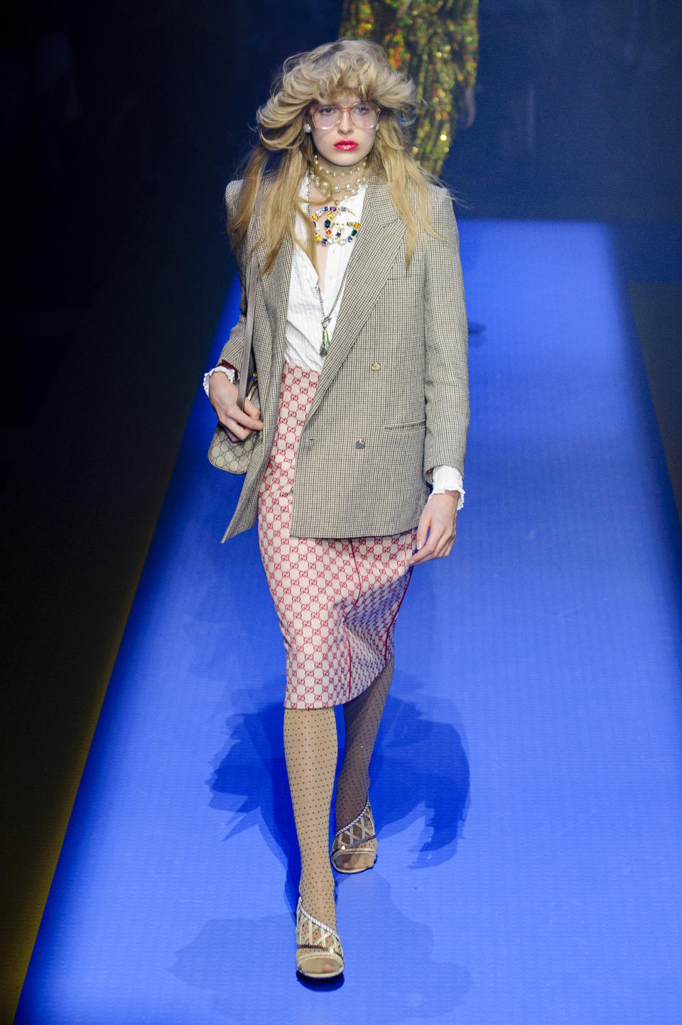 <p><i>Model wears a plaid blazer and red Gucci logo skirt, with a white shirt and layered bright jewelry. (Photo: ImaxTree) </i></p>