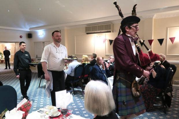 Kieron Cooney on the bagpipes, followed by chef de cuisine Alan Reeves, bearing the haggis, and New Holmwood Hotel staff member carrying five tots of whisky. Photo by Helen Danby.