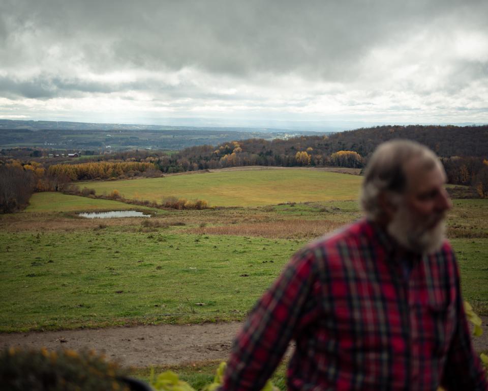 Ben Simons stands out on the back porch of his home with his farmland in the background atop of Starr Hill in Remsen, NY. He was approached by a land agent interested in leasing acres of Simons’ land to build an array of solar panels to convert the sun’s energy into electricity and deliver it to the state’s electrical grid.