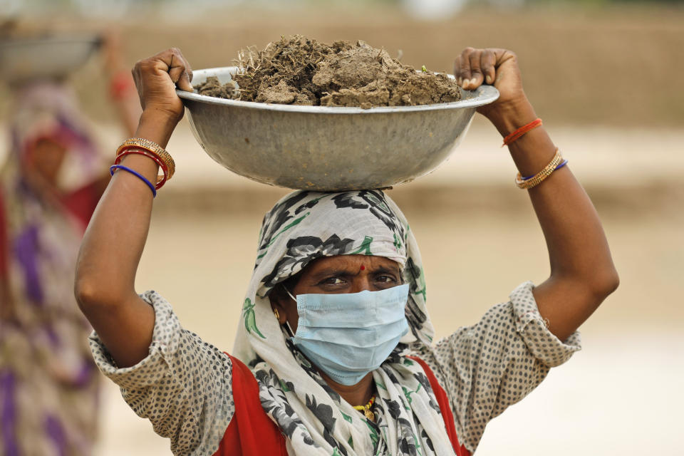 A daily wage laborer works to construct a village pond under the National Rural Employment Guarantee Act in Araipur Gherva village on the outskirts of Fatehpur, in the northern Indian state of Uttar Pradesh, Sunday, June 28, 2020.  The Act aims at removing poverty by assuring at least 100 days' employment  to every rural household. (AP Photo/Rajesh Kumar Singh)