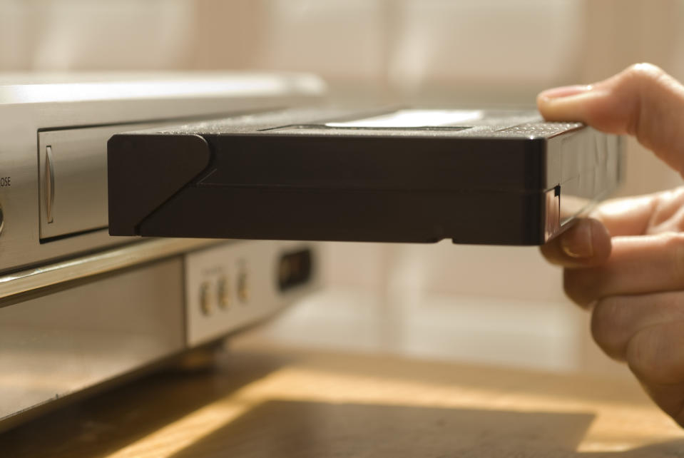 Hand inserting a VHS tape into a VCR, reminiscent of past home entertainment technology