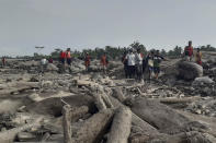 Rescuers and villagers carry a body bag containing the remains of a victim in the eruption of Mount Semeru, in Candi Puro village, Lumajang, East Java, Indonesia, Tuesday, Dec. 7, 2021. Indonesia's president on Tuesday visited areas devastated by a powerful volcanic eruption that killed a number of people and left thousands homeless, and vowed that communities would be quickly rebuilt. (AP Photo/Rokhmad)