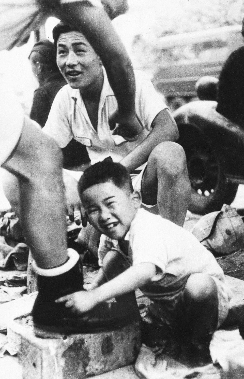 A war orphan polishes shoes in downtown Tokyo on Aug. 1, 1946. In Japan, war orphans were punished for surviving. They were bullied. They were called trash, sometimes rounded up by police and put in cages. Some were sent to institutions or sold for labor. They were targets of abuse and discrimination. A 1948 government survey found there were more than 123,500 war orphans nationwide. But orphanages were built for only for 12,000, leaving many homeless. (Kyodo News via AP)