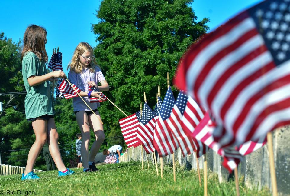 Izzy Morrison, left, and Emmalyn Perkins place American flags at the gravestones in Antietam National Cemetery on Thursday. The tradition is for fifth graders from the school to place nearly 5,000 of the flags at the stones to commemorate Memorial Day.