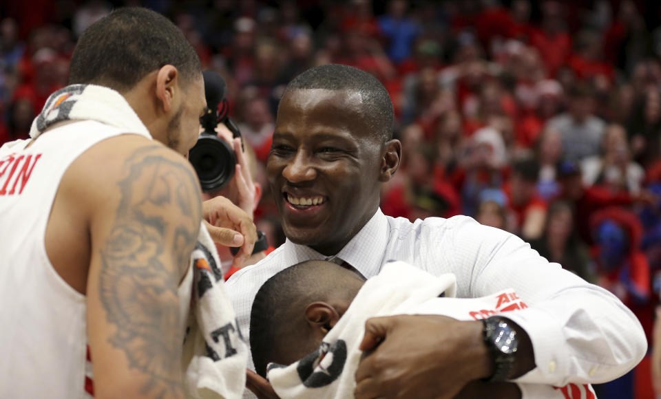 FILE - In this March 7, 2020, file photo, Dayton head coach Anthony Grant celebrates with Obi Toppin, left, and Jalen Crutcher, bottom right, after their win in an NCAA college basketball game against George Washington, in Dayton, Ohio. Toppin and Grant have claimed top honors from The Associated Press after leading the Flyers to a No. 3 final ranking. Toppin was voted the AP men's college basketball player of the year, Tuesday, March 24, 2020. Grant is the AP coach of the year. (AP Photo/Tony Tribble, File)