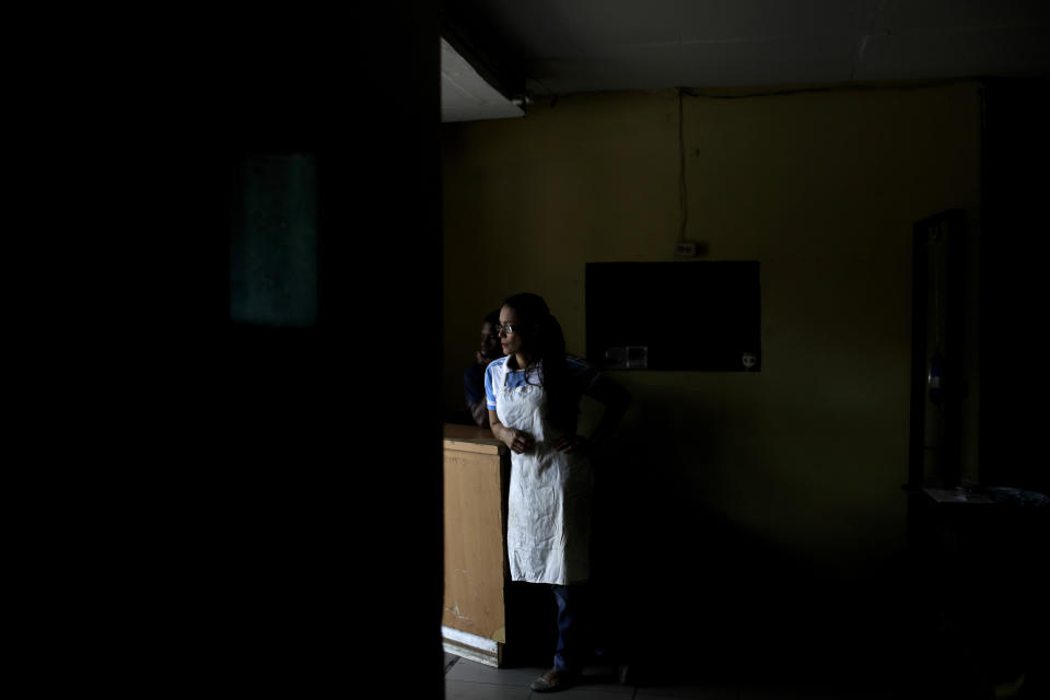 FILE - In this March 26, 2019 file photo, Estela Garcia stands inside the grocery shop where she works, during a blackout, in Caracas, Venezuela. A new power outage spreads across much of Venezuela, knocking communications offline. (AP Photo/Natacha Pisarenko, File)