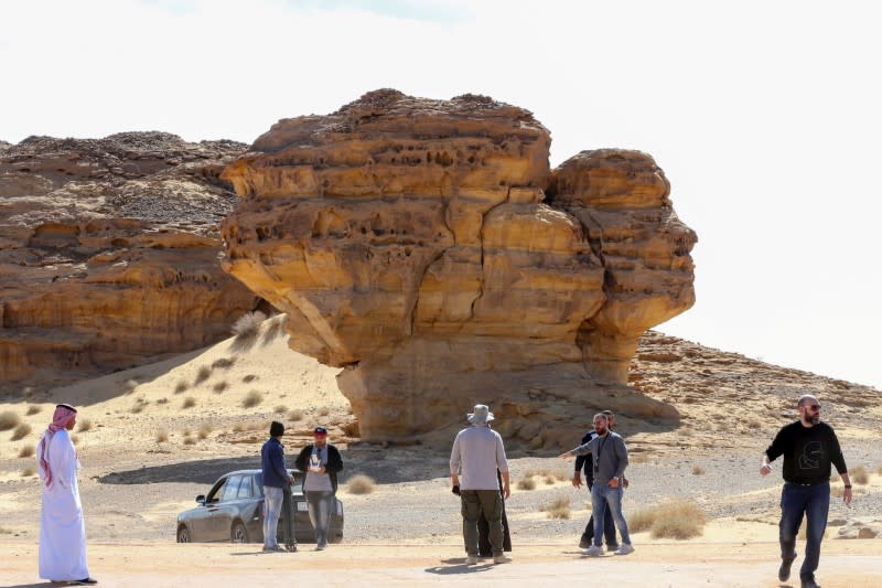 Visitors tour near Rock formations that resemble human face at the Madain Saleh antiquities site in Al-Ula