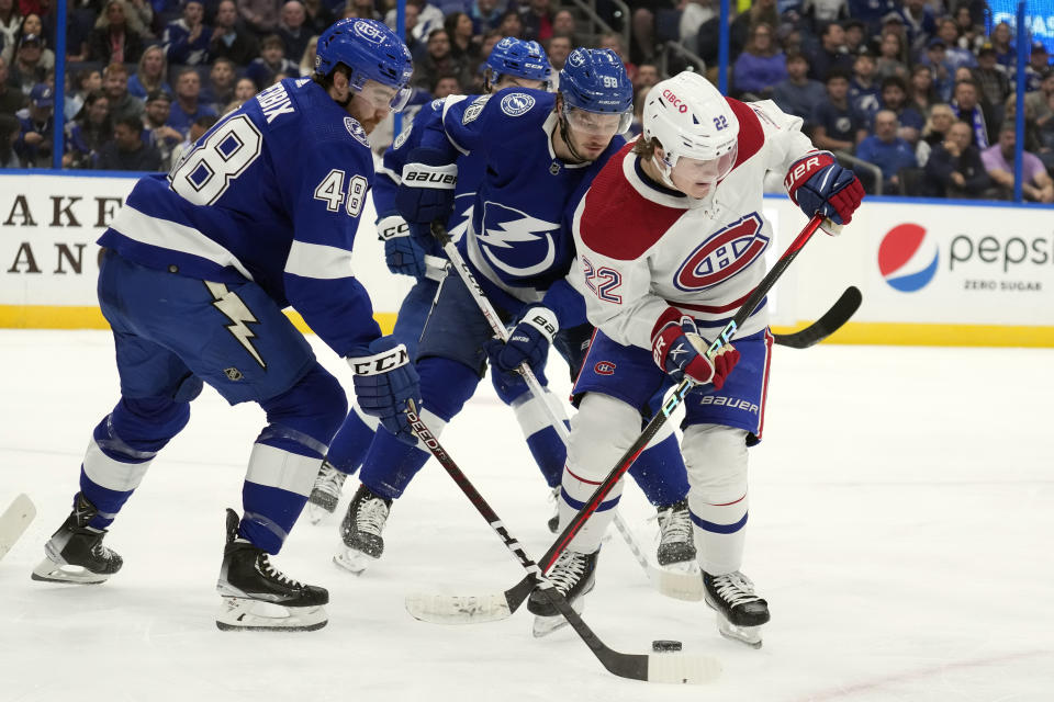 Montreal Canadiens right wing Cole Caufield (22) works the puck against Tampa Bay Lightning defenseman Nick Perbix (48) and defenseman Mikhail Sergachev (98) during the first period of an NHL hockey game Wednesday, Dec. 28, 2022, in Tampa, Fla. (AP Photo/Chris O'Meara)