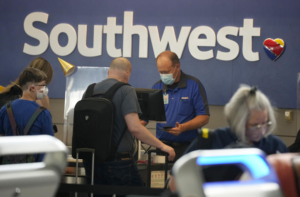 FILE - In this Wednesday, June 16, 2021, file photo, a Southwest Airlines ticketing agent helps a traveller at the check-in counter at Denver International Airport in Denver. This summer is already shaping up to be a difficult one for air travelers. Southwest Airlines customers have struggled with thousands of delays and hundreds of canceled flights this month because of computer problems, staffing shortages and bad weather. (AP Photo/David Zalubowski, File)