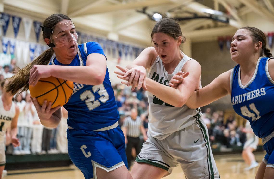 Caruthers Blue Raiders forward/guard Emmi Almeida (23), left, and center Mia Nola (41) try to keep the ball from Colfax Falcons center Juliette James (55) during the first quarter of the CIF Northern California Division III high school girls basketball championship game Tuesday, March 7, 2023, at Colfax High School.