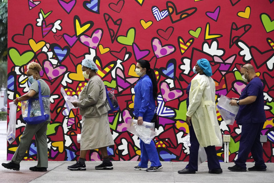 Healthcare workers line up for free personal protective equipment in front of a mural by artist Romero Britto at Jackson Memorial Hospital, Tuesday, Sept. 22, 2020, in Miami. Hundreds of workers lined up for the PPE given out by the New York nonprofit Cut Red Tape 4 Heroes. (AP Photo/Wilfredo Lee)