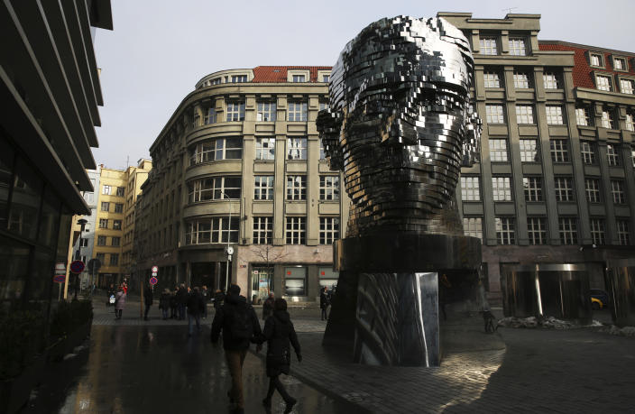 FILE - In this Feb. 4, 2017 file photo, tourists walk past a moving metal sculpture of writer Franz Kafka in his birth city of Prague, Czech Republic, on Saturday, Feb. 4, 2017. A long-hidden trove of unpublished works by Franz Kafka could soon be revealed following a decade-long battle over his literary estate that has drawn comparisons to some of his surreal tales. (AP Photo/Jon Gambrell, File)