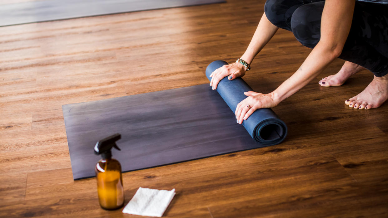  Woman rolling up a yoga mat after cleaning 