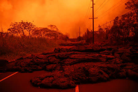 FILE PHOTO: Lava covers a road near Pahoa during ongoing eruptions of the Kilauea Volcano in Hawaii, U.S., June 8, 2018. REUTERS/Terray Sylvester