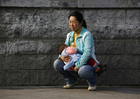 A Chinese woman crouches as she breastfeeds her child along a street in central Beijing in this October 30, 2008 file photo. REUTERS/David Gray/Files