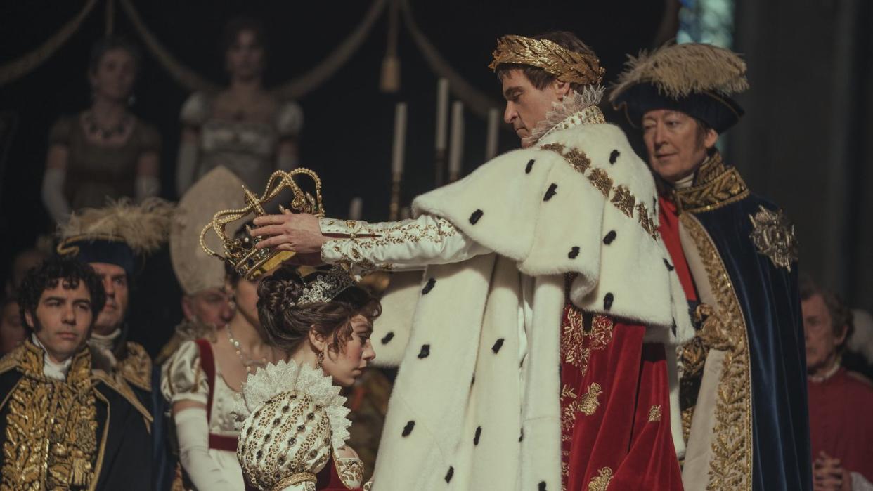 joaquin phoenix as napoleon bonaparte placing a crown on the head of wife josephine played by vanessa kirby