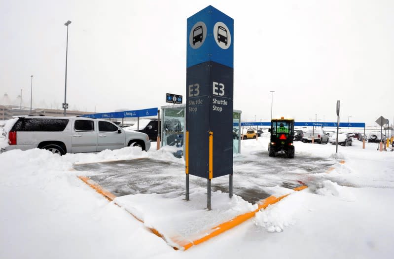 An airport worker clears a shuttle stop after a snowstorm at Denver International Airport