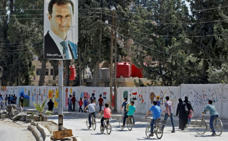 A portrait of Syria's President Bashar al-Assad overlooks students heading back to school in the former rebel-held enclave of Eastern Ghouta