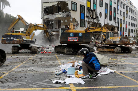 An employee of collapsed Marshal hotel collects items from debris while excavators demolish the hotel after an earthquake hit Hualien, Taiwan February 9, 2018. REUTERS/Tyrone Siu