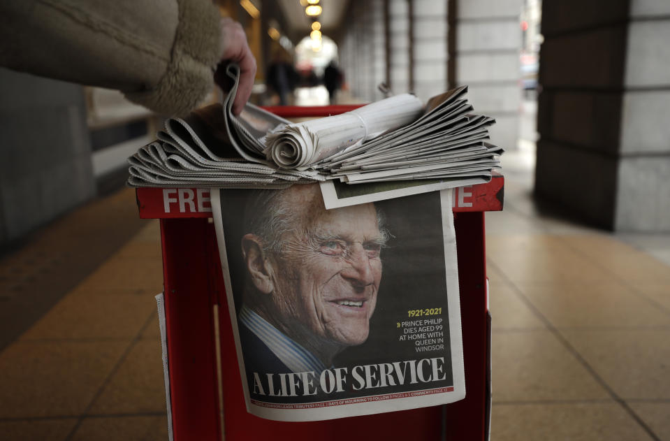 A person takes a copy of a newspaper with a tribute to Britain's Prince Philip on the front page at Leicester Square in London, Friday, April 9, 2021. Buckingham Palace officials say Prince Philip, the husband of Queen Elizabeth II, has died. He was 99. Philip spent a month in hospital earlier this year before being released on March 16 to return to Windsor Castle. (AP Photo/Matt Dunham)