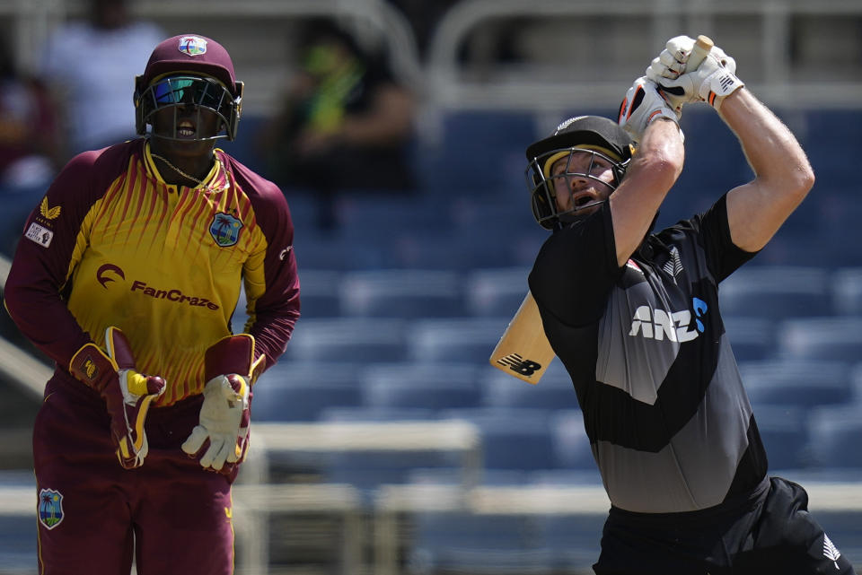 New Zealand's Glenn Phillips eyes the ball under the watchful eyes of West Indies' wicket keeper Devon Thomas during the third T20 cricket match at Sabina Park in Kingston, Jamaica, Sunday, Aug. 14, 2022. (AP Photo/Ramon Espinosa)