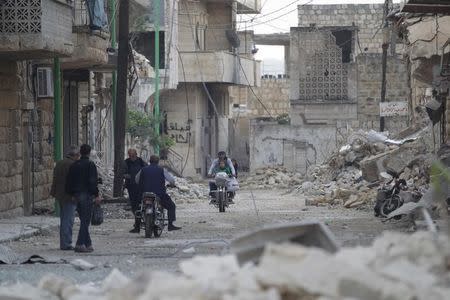 Civilians walk as others ride motorbikes past damaged buildings in the rebel-controlled area of Maaret al-Numan town in Idlib province, Syria October 29, 2015. REUTERS/Khalil Ashawi