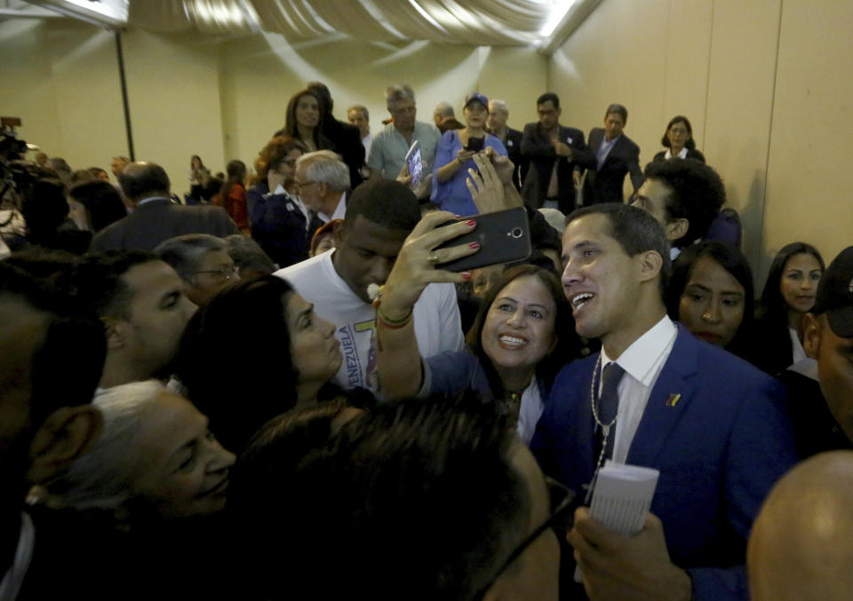Venezuela's opposition leader and self-proclaimed interim president Juan Guaido, right, poses for selfies with supporters, after a meeting at a hotel in Valencia, Venezuela, June 7, 2019. A member of Venezuela's opposition said that a mediation effort by Norway is stalling over Nicolás Maduro's refusal to accept presidential elections to resolve the nation's political crisis. (AP Photo/Juan Carlos Hernandez)