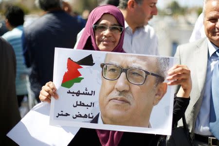 A woman holds a picture of Jordanian writer Nahed Hattar, who was shot dead, during a sit-in in front of the prime minister's building in Amman, Jordan, September 26, 2016. REUTERS/Muhammad Hamed