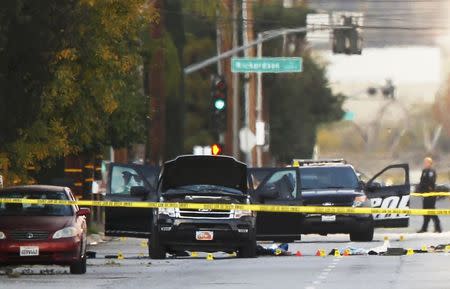 A police investigator is seen around a vehicle (C) in which two suspects were shot following a mass shooting in San Bernardino, California December 3, 2015. REUTERS/Mike Blake